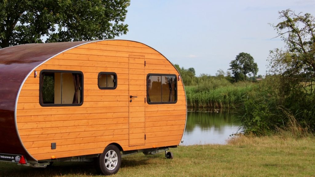 Aussenansicht eines Holz Caravans mit drei Fenstern und einer Tür im Urlaub am Wasser